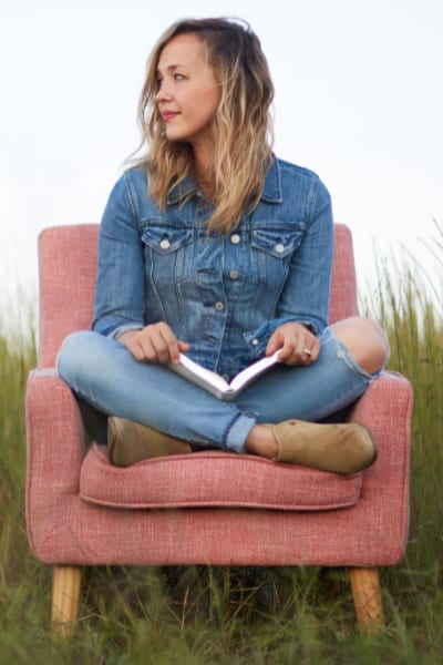 Woman sitting in pink chair with an open book in her lap