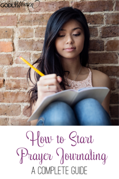 Young woman prayer journaling in a notebook with a pencil