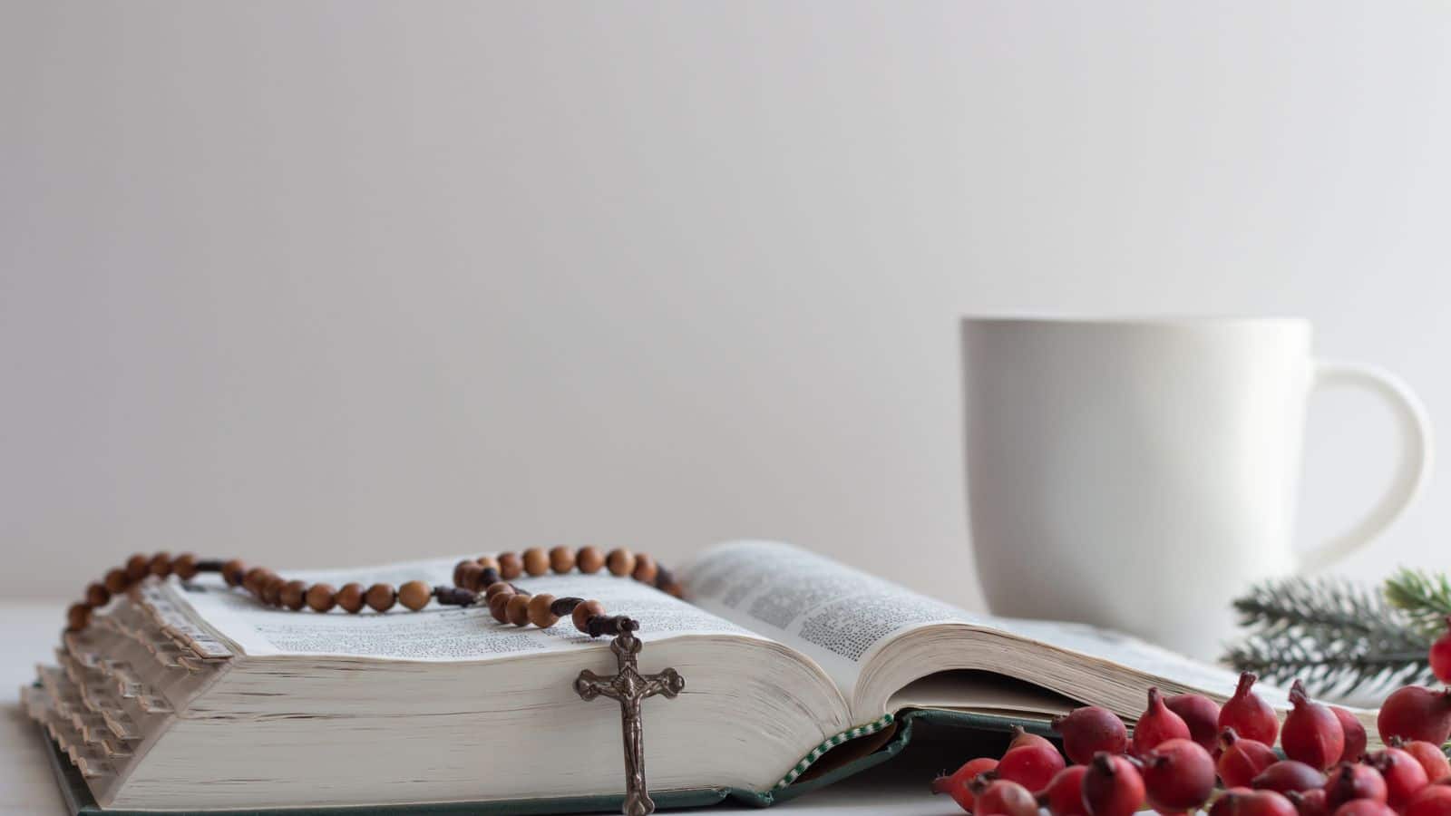 rosary on bible with cup and berries