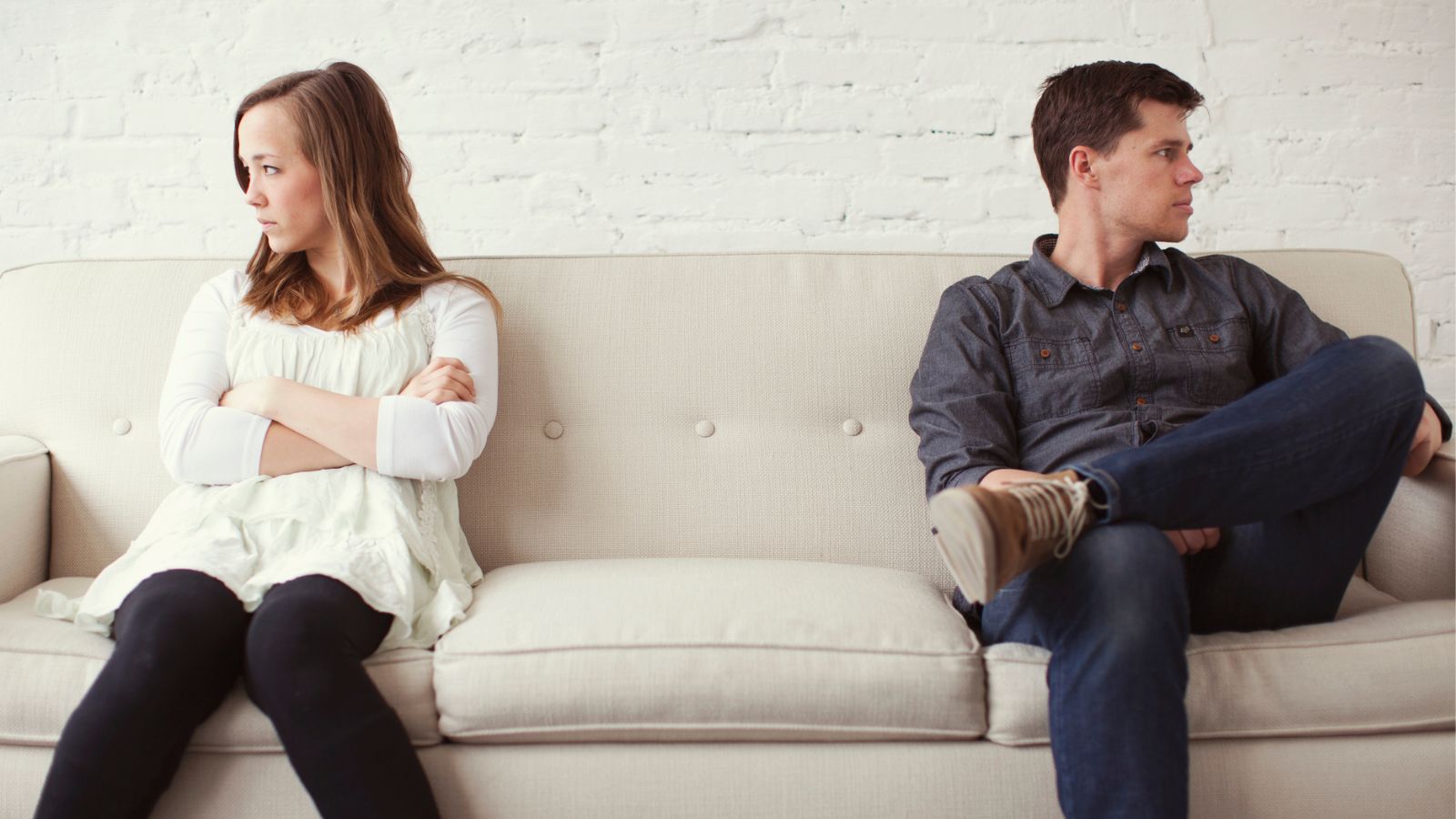 Angry man and woman sitting on opposite sides of a couch