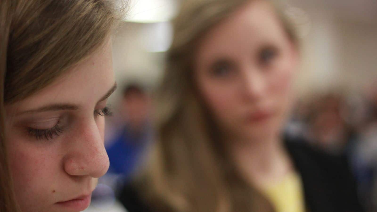 Girl looking at another girl with unhappy expression