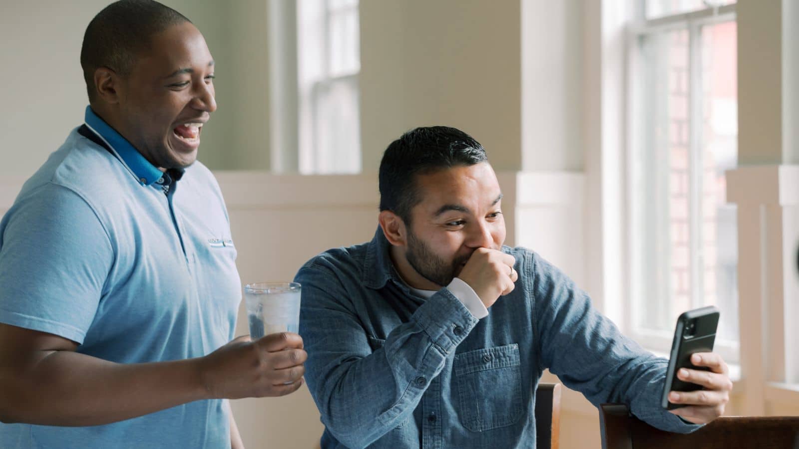 Two men looking at a phone and laughing