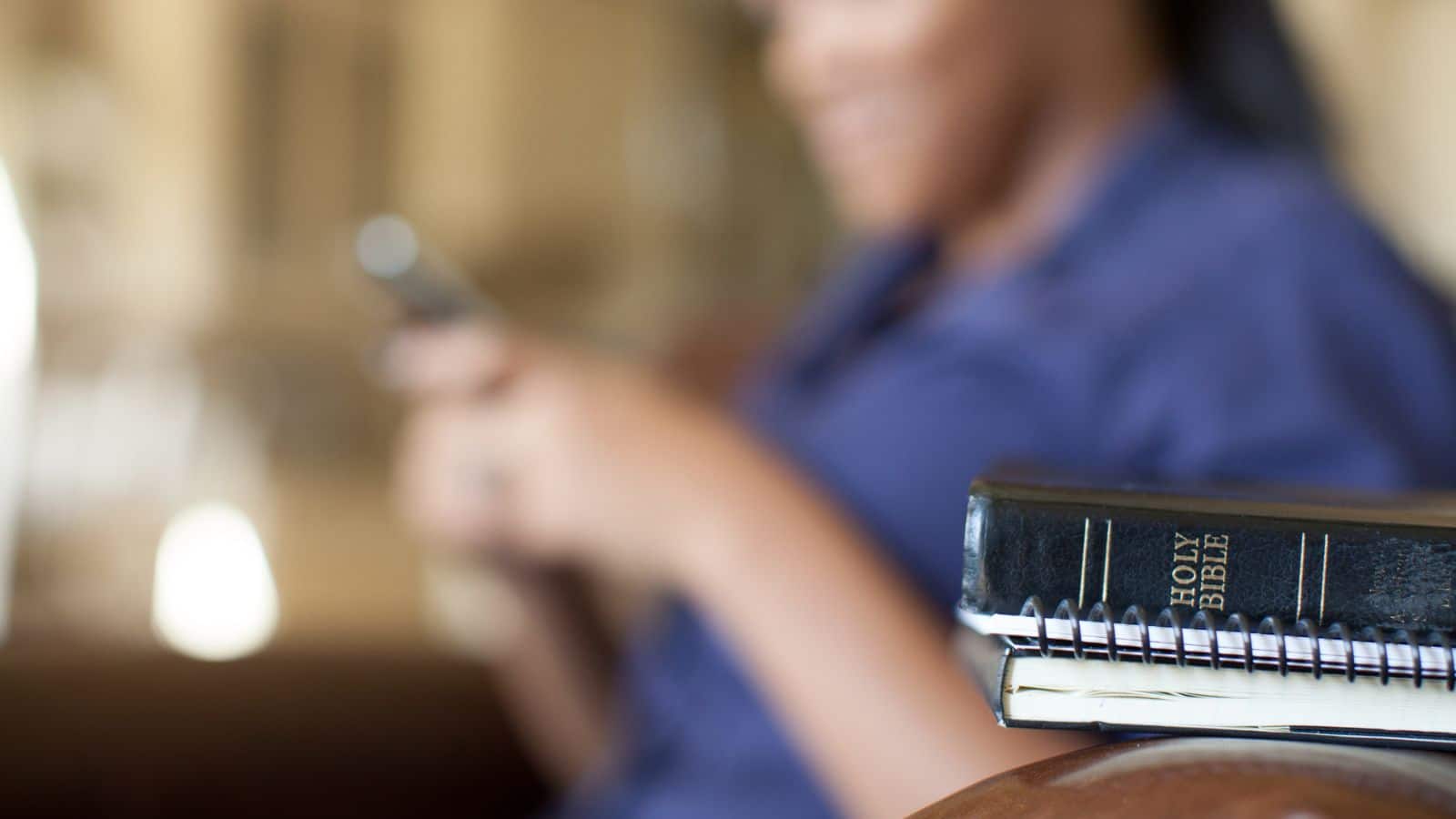 Woman playing on phone instead of reading her Bible