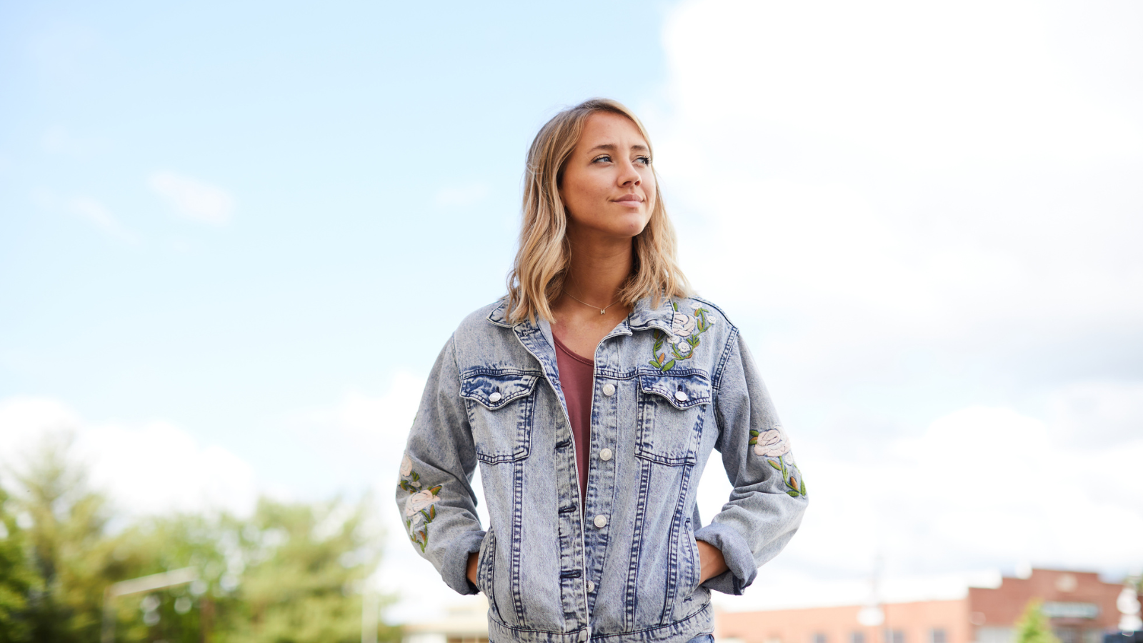 Confident girl in jean jacket looking to the sky outside