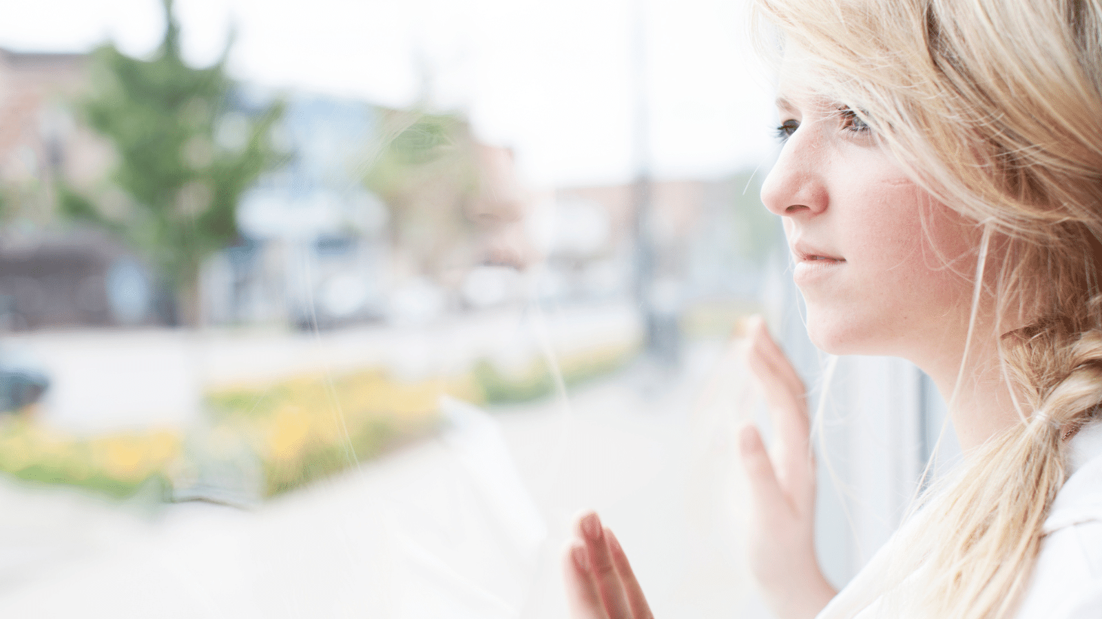 Girl looking out window with hands on glass