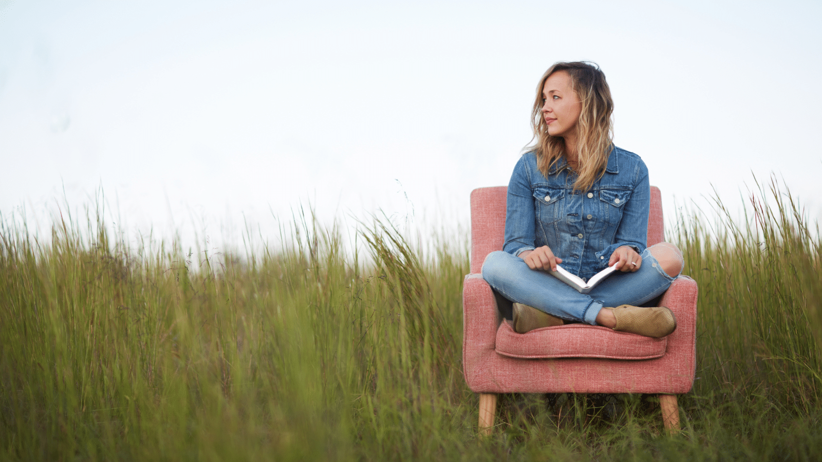 Girl sitting on a chair looking out across a field