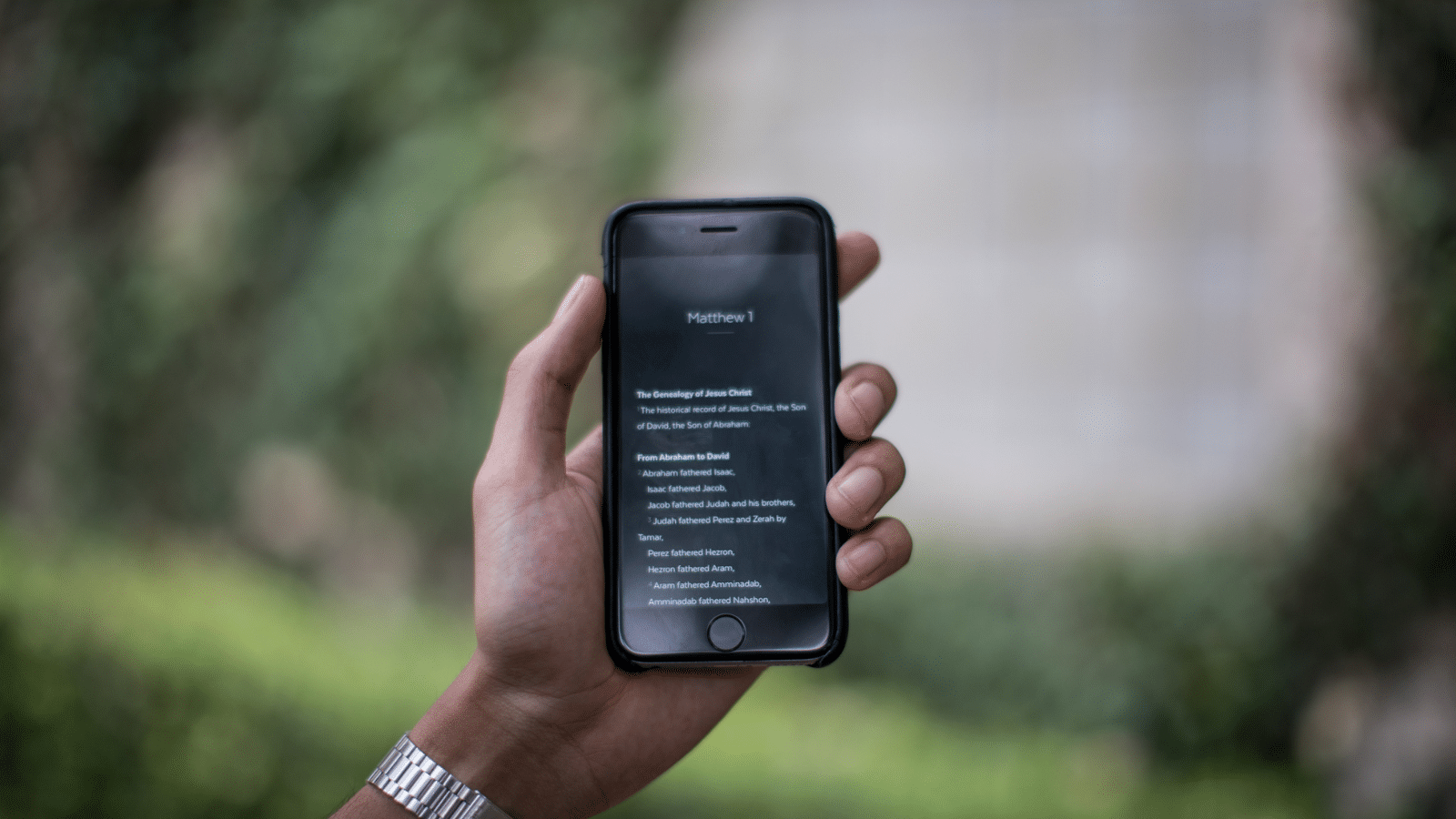 Man's hand holding phone with Bible verses on it