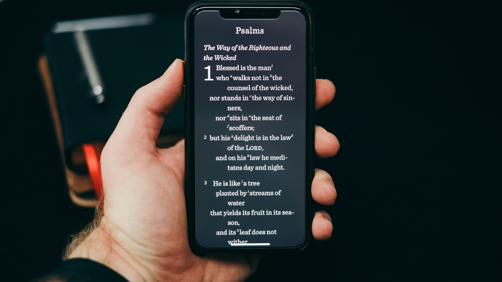 Man's hand holding phone with Bible verses on it