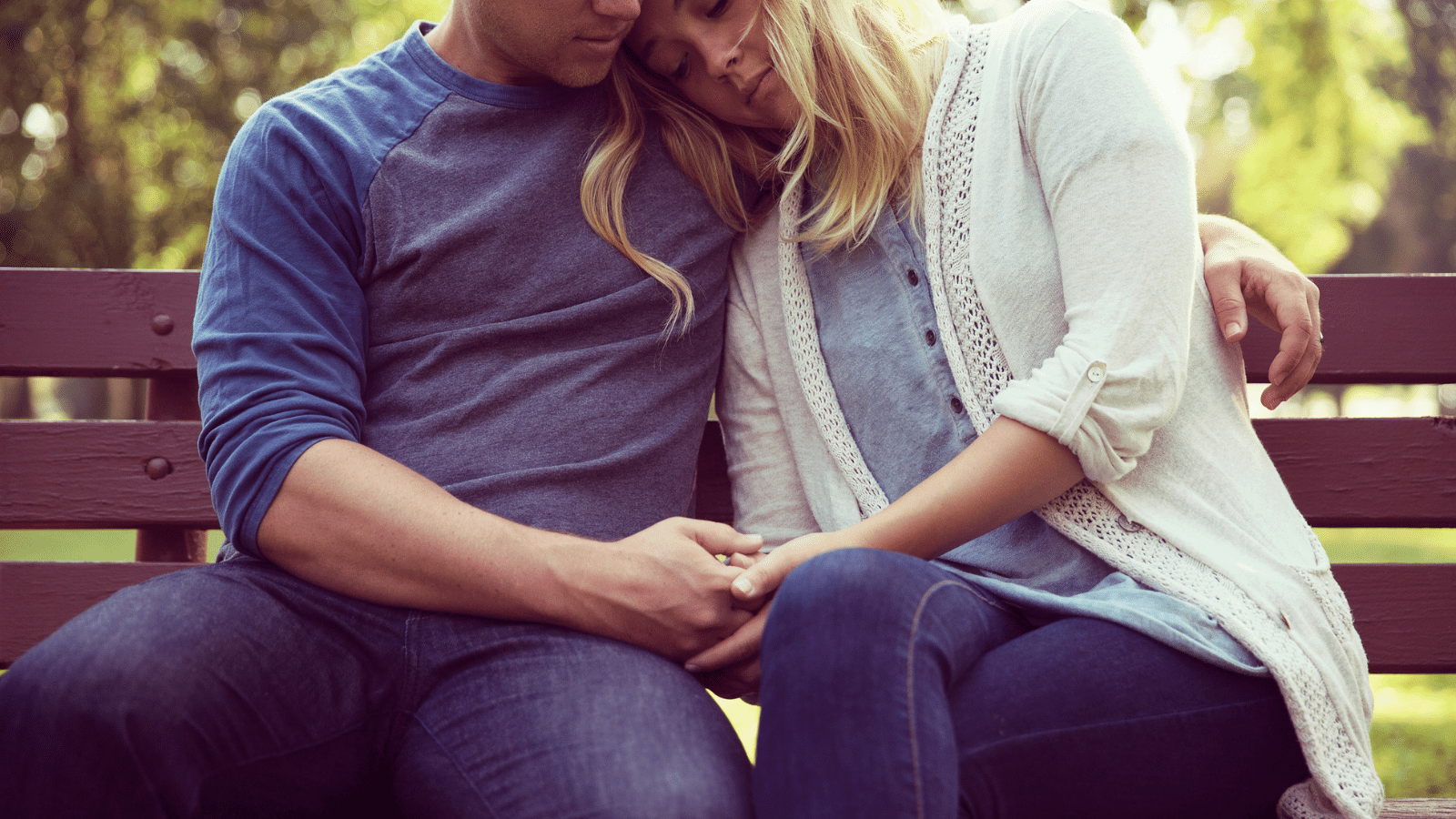 a couple snuggling on a park bench