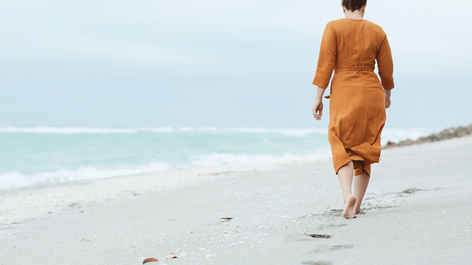 woman walking away barefoot on a beach
