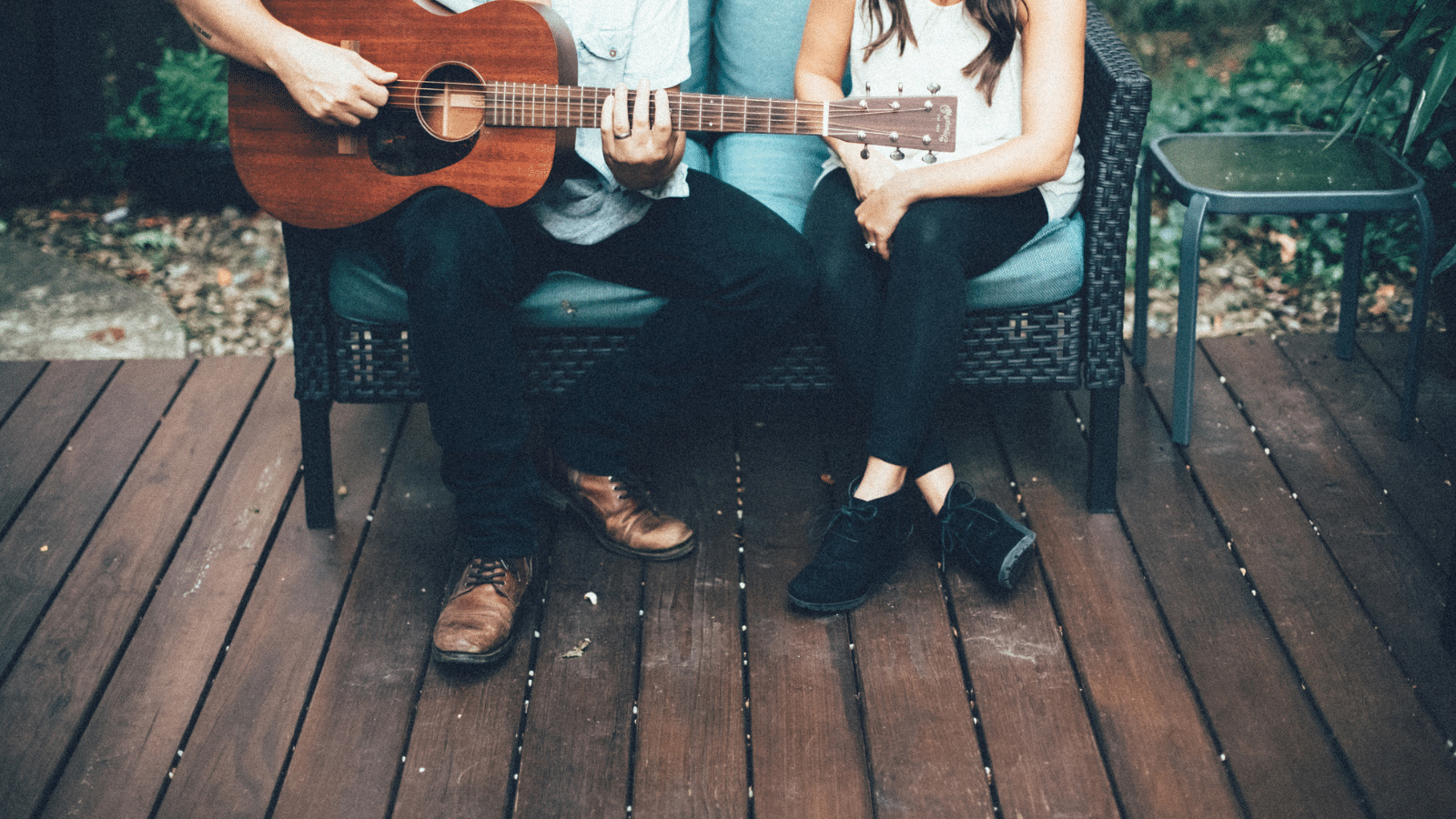 couple with guitar sitting on bench