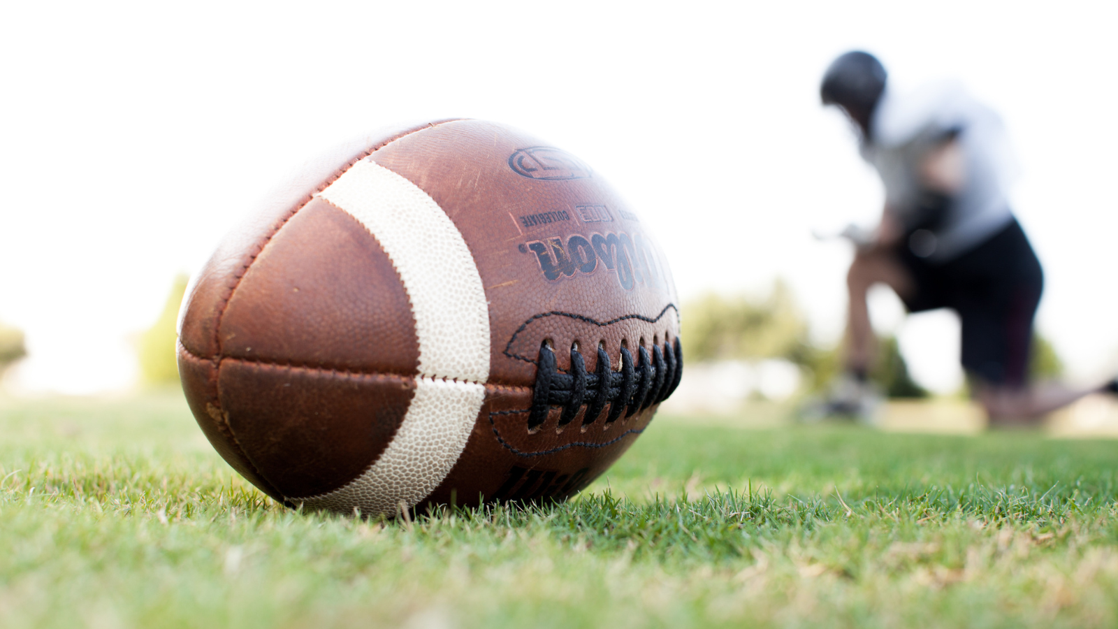 football player kneeling with football on ground
