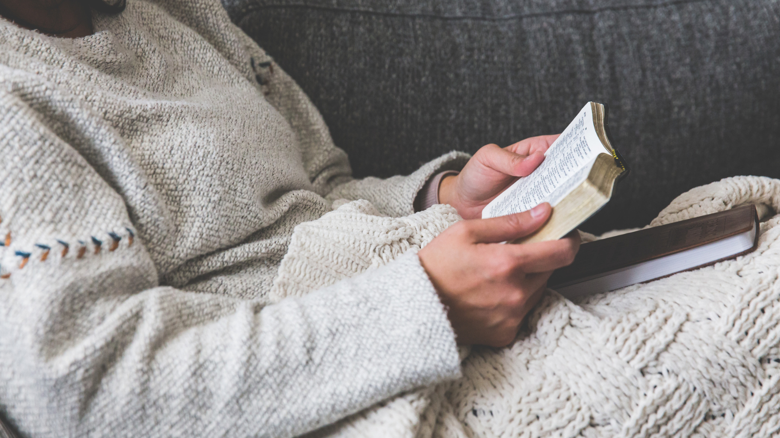 reading on a couch with blanket and small Bible