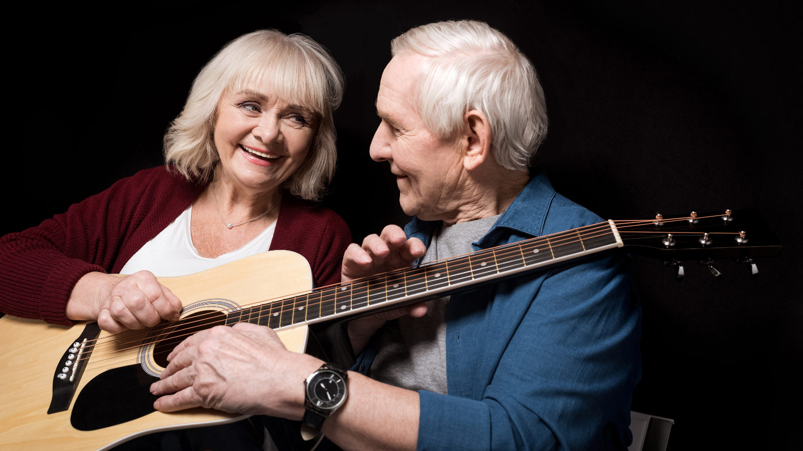 couple playing guitar smiling