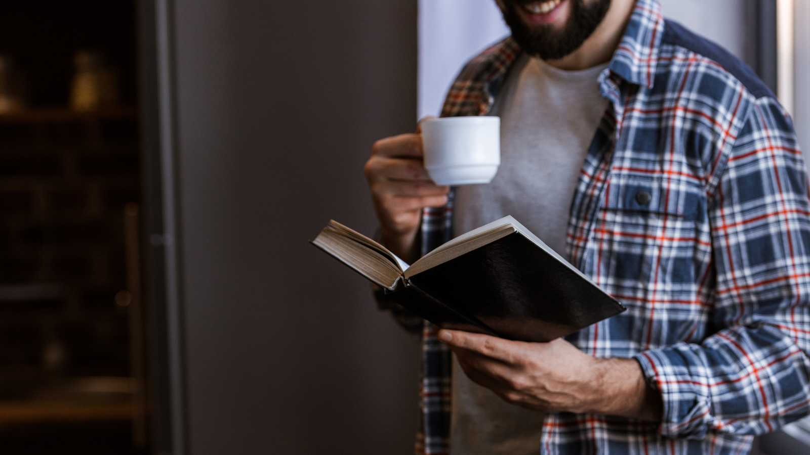 man reading with cup of coffee and flannel shirt