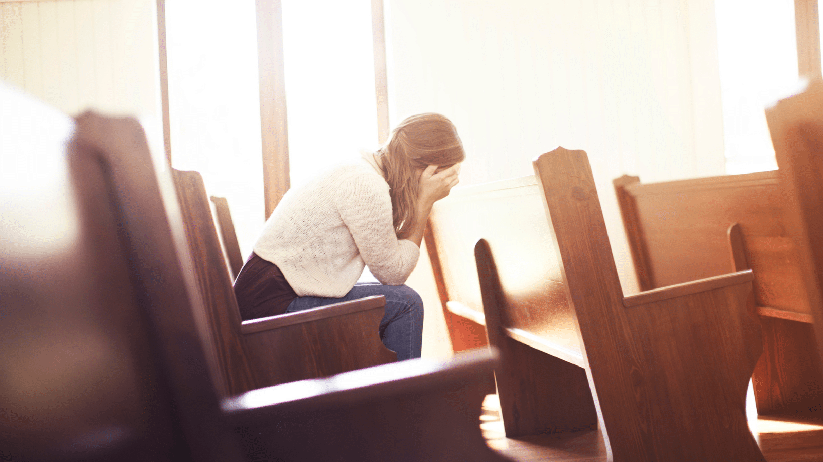 Woman with hands covering her face in church
