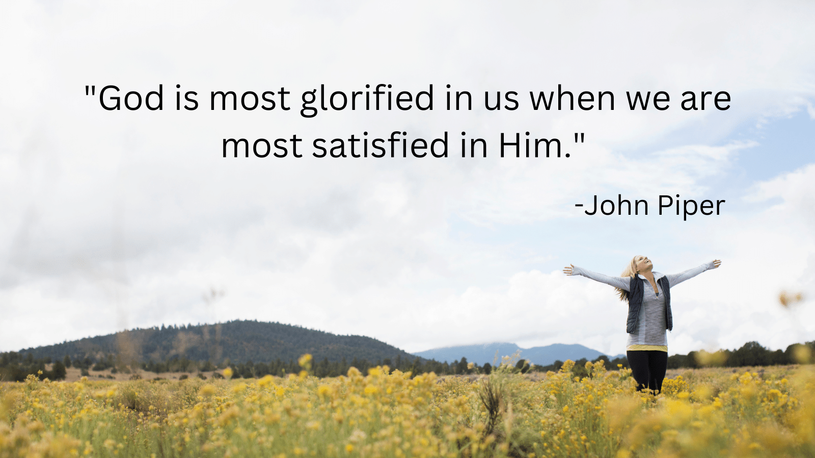Woman standing in a field with arms in the air and John Piper quote