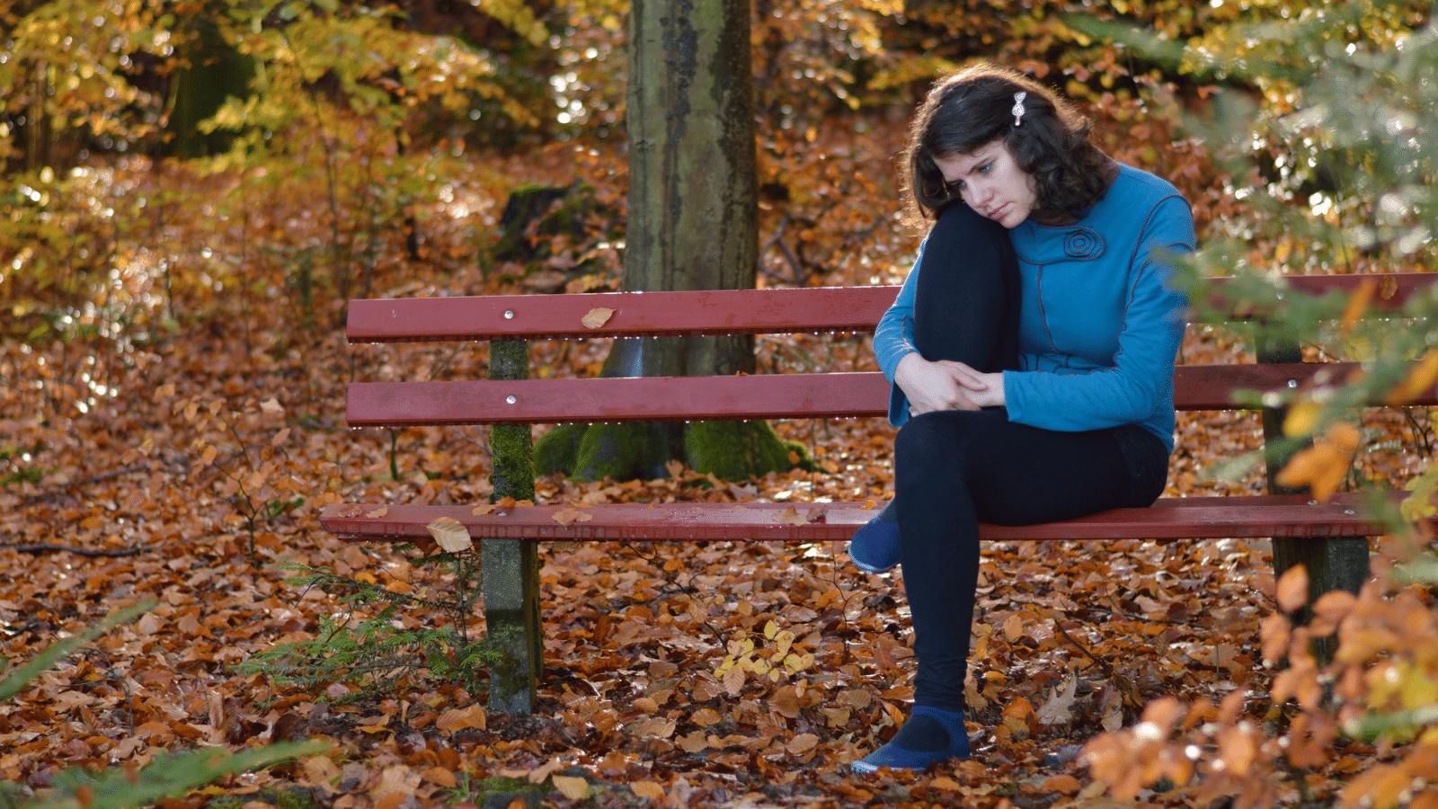 woman sad on a park bench outside