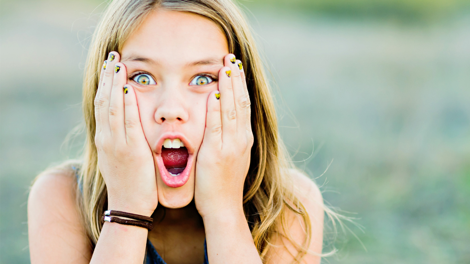 Tween girl with her hands on her face and mouth opened in shock