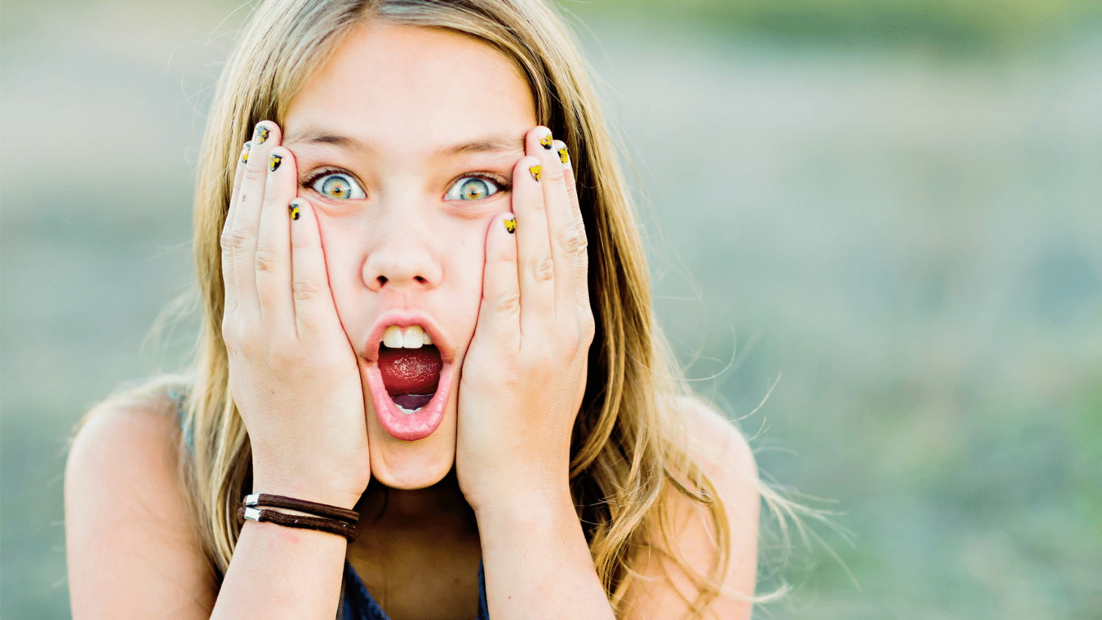 Tween girl with her hands on her face and mouth opened in shock