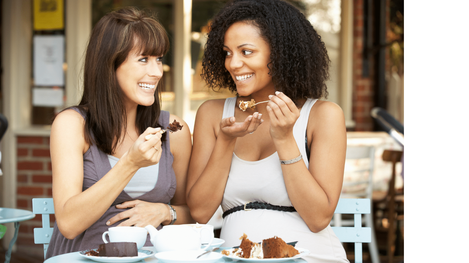 Two women, enjoying cake and coffee, laughing with each other. Eat, drink, and be merry.