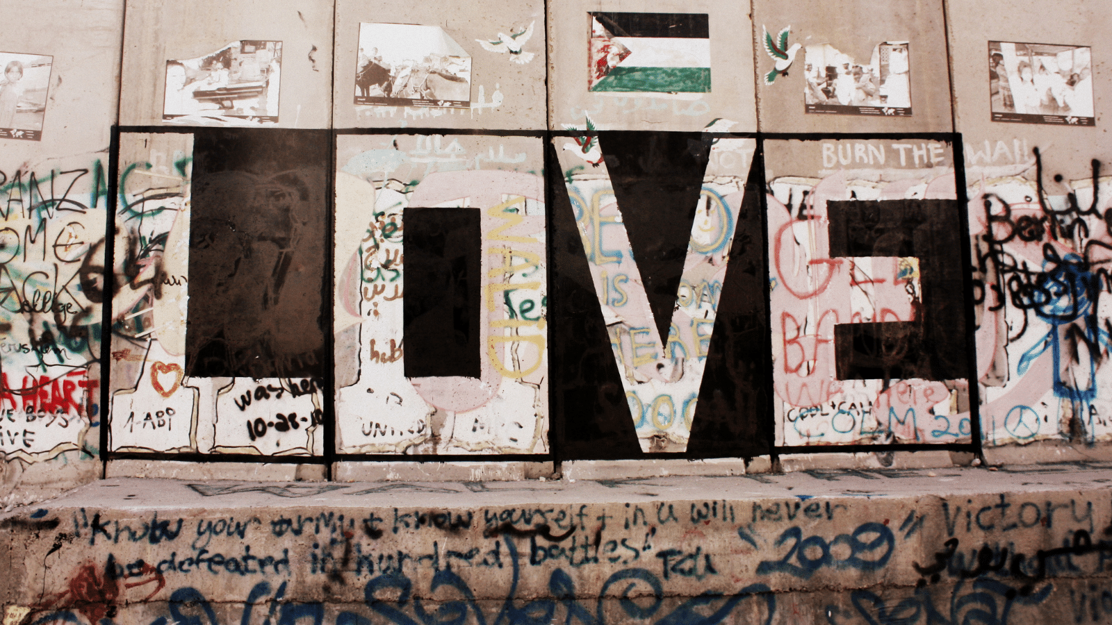 The word "love" graffitied a wall, with other writing all around it.