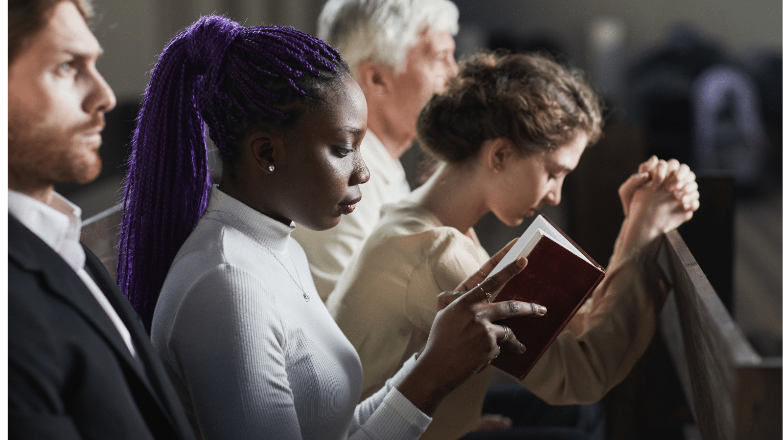 Women sitting next to their husbands in church, one woman praying, one woman reading her Bible.