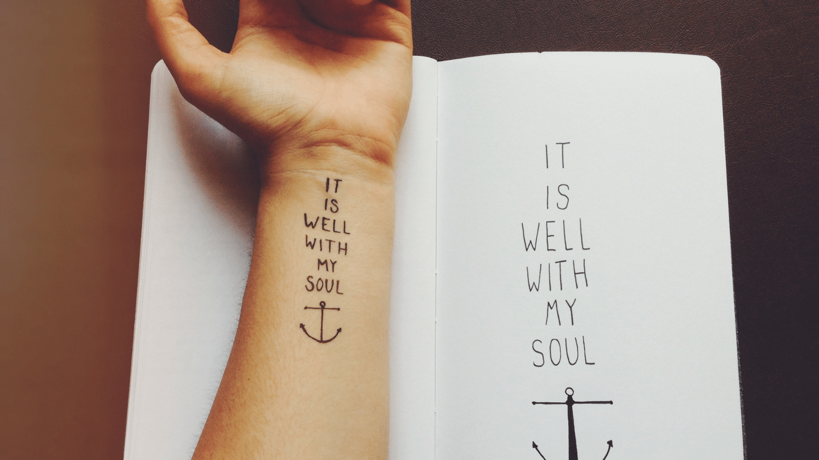 arm with It is well with my soul tattoo and anchor