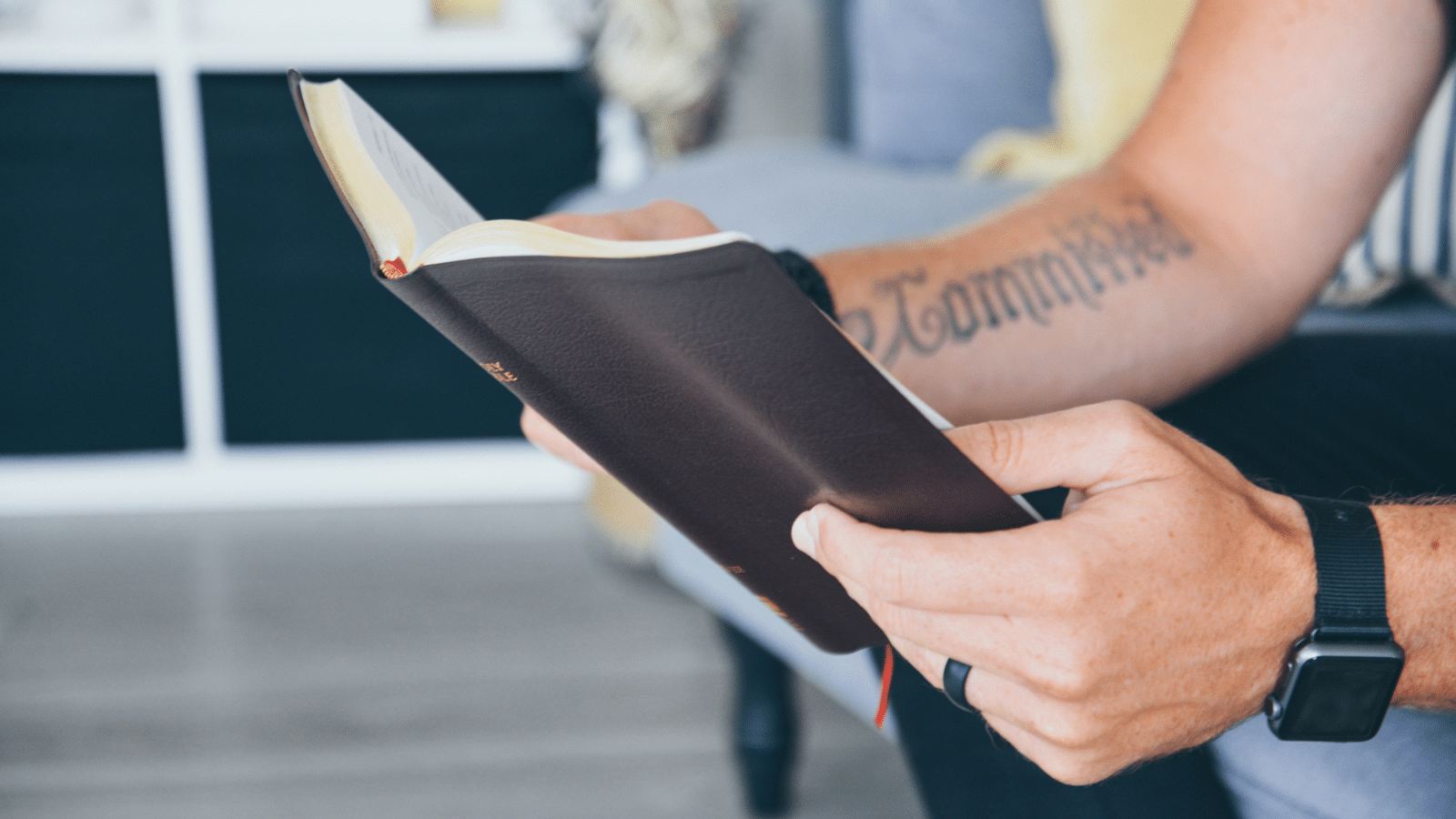 man reading Bible with committed tattoo