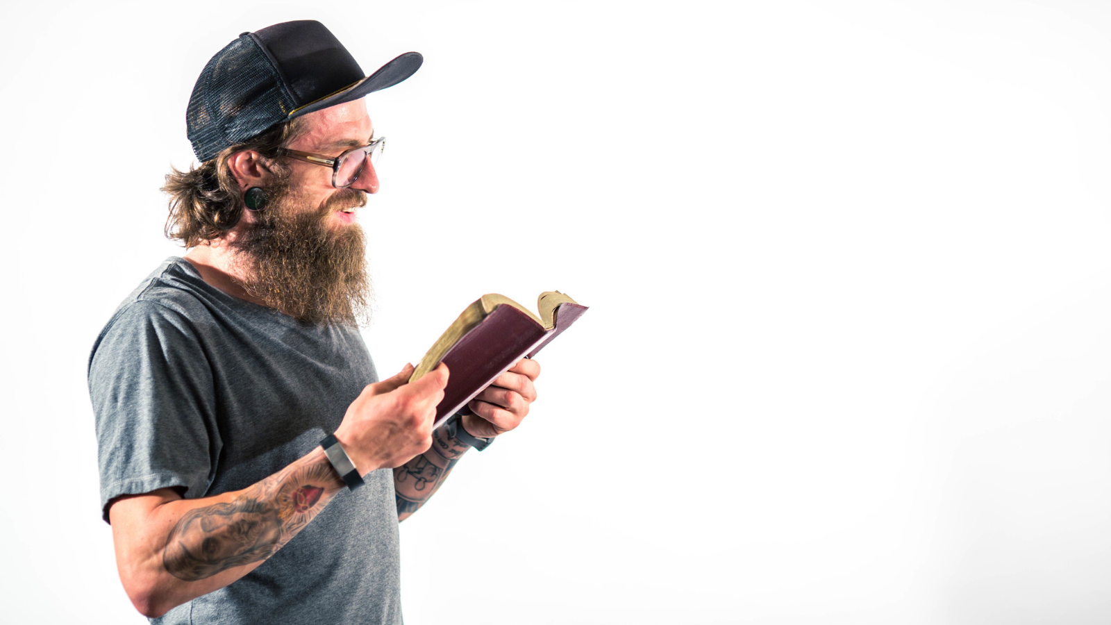 man reading Bible with tattoo