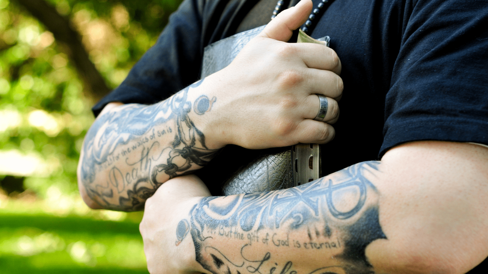 man with Christian tattoos holding a Bible