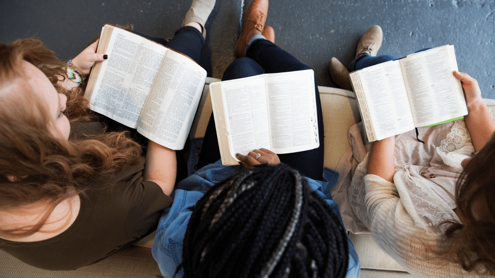 overhead shot of three girls reading the Bible together