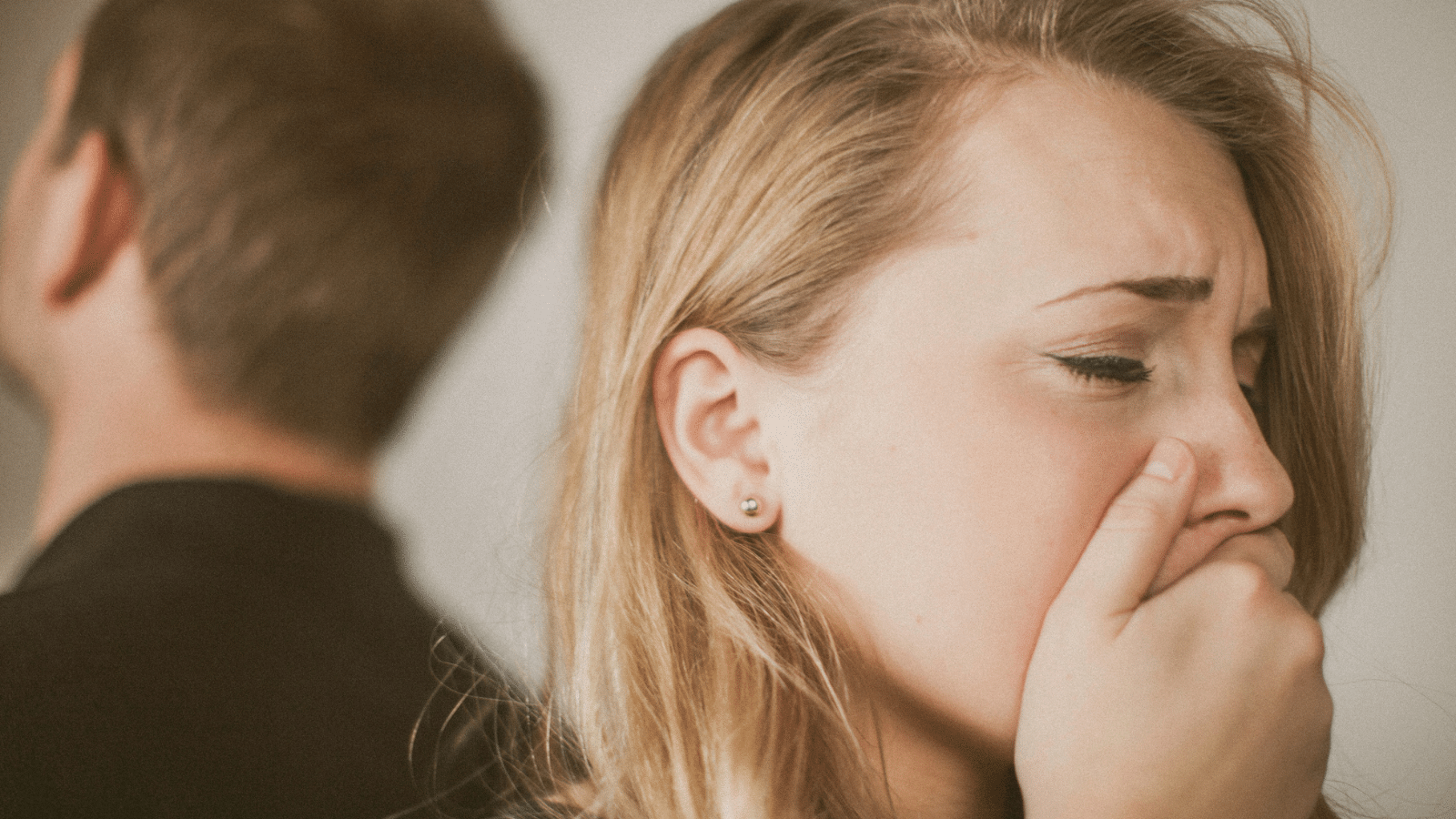 woman covering mouth looking sad