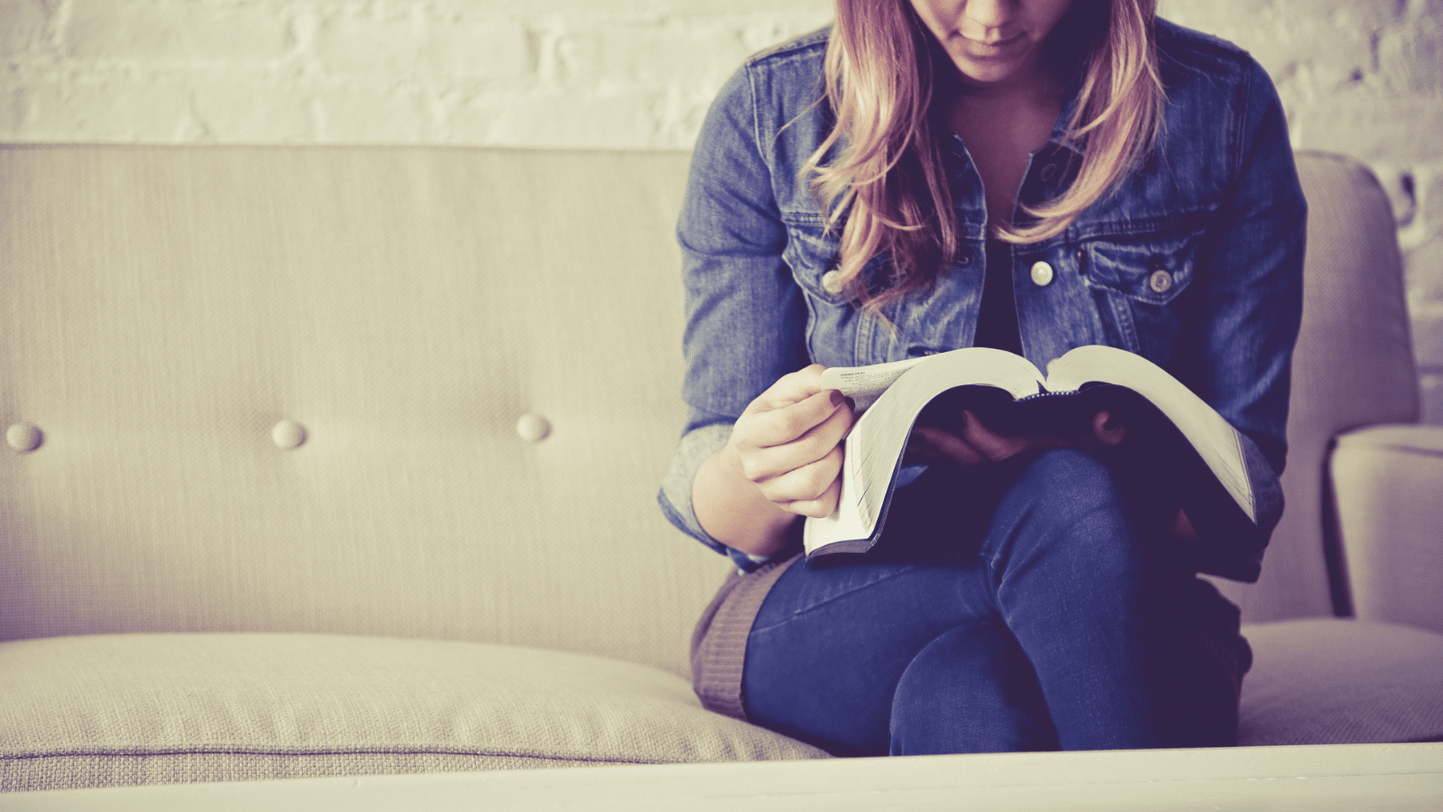 woman reading Bible on the couch