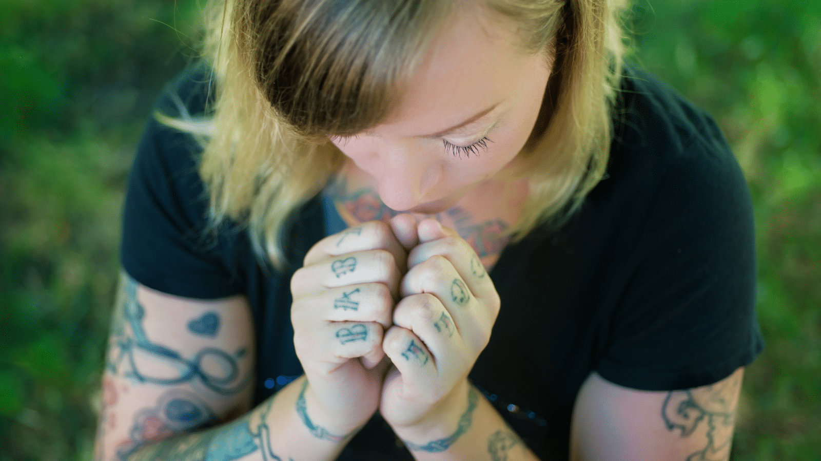woman with lots of tattoos praying