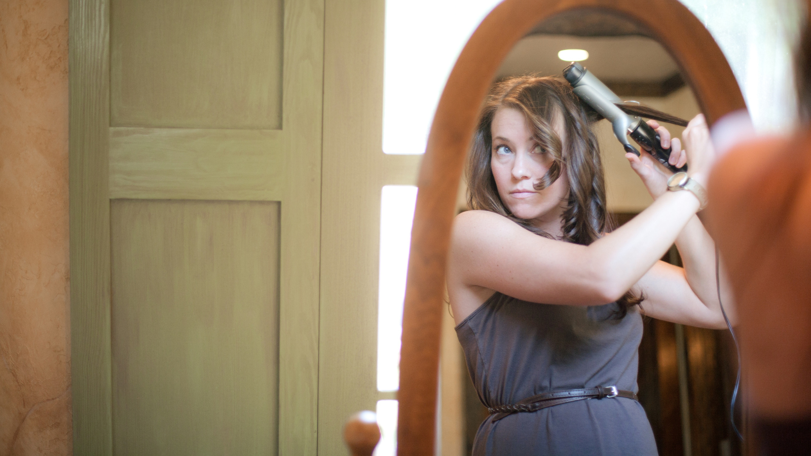 woman curling hair in mirror