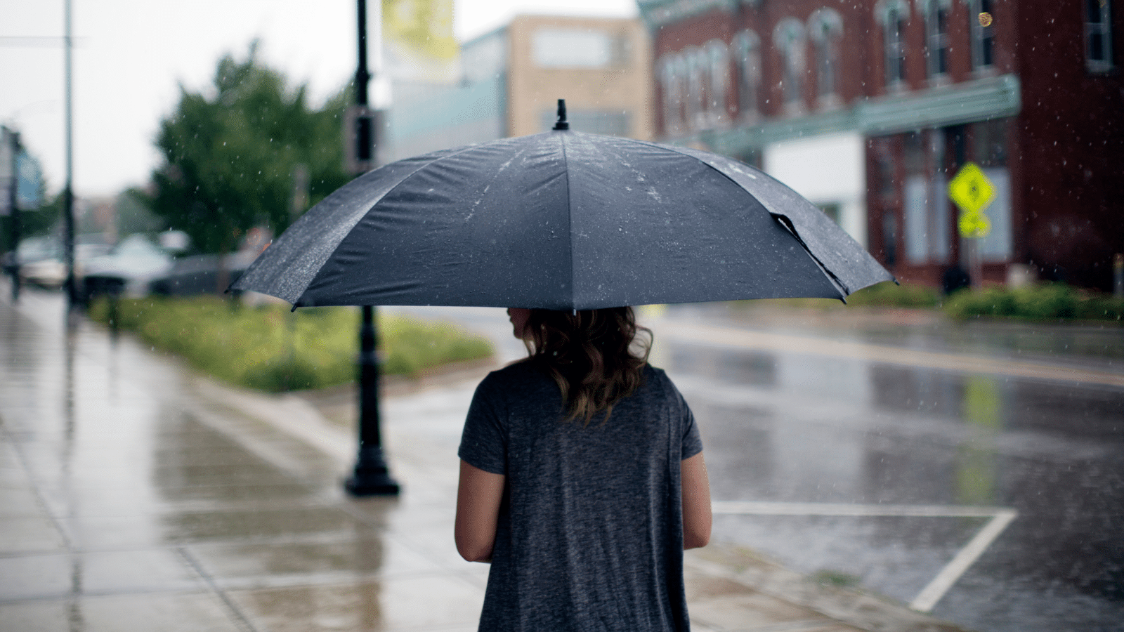 woman walking in rain with umbrella