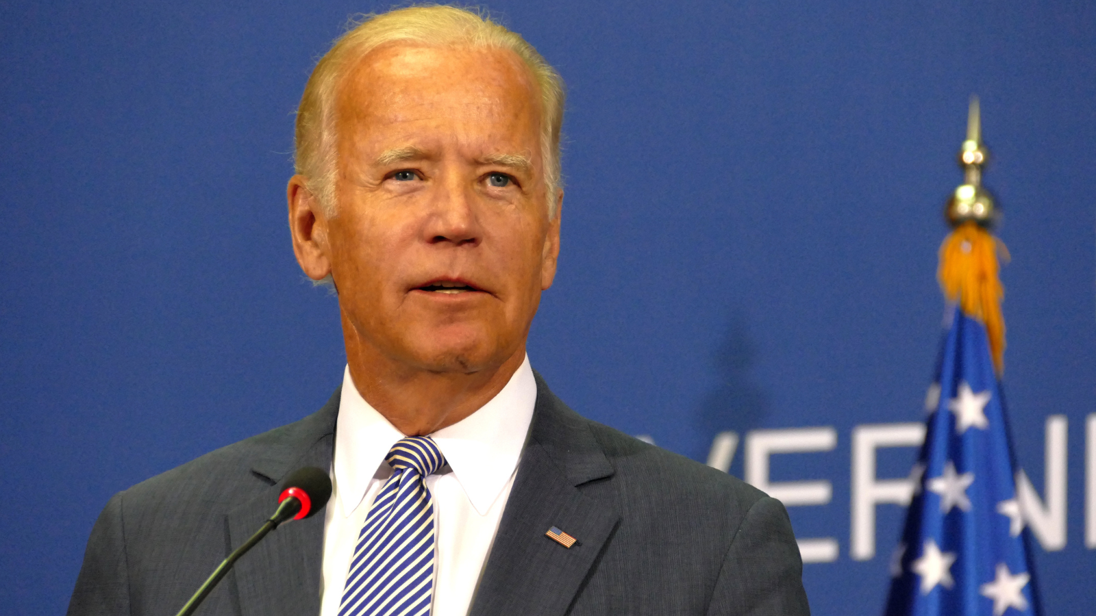 Joe Biden standing in front of a blue background.