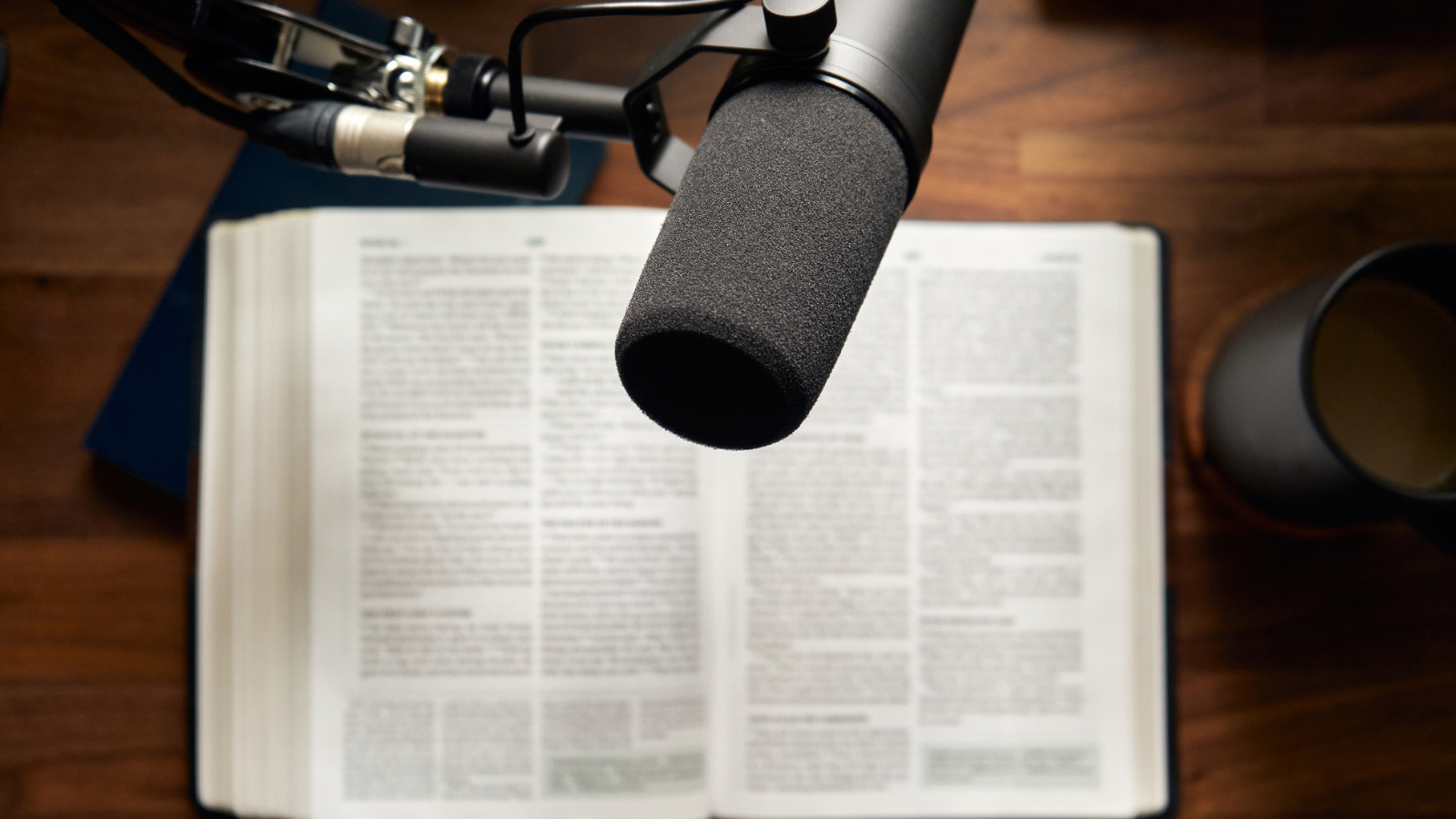 An open bible wit ha podcast microphone above it.