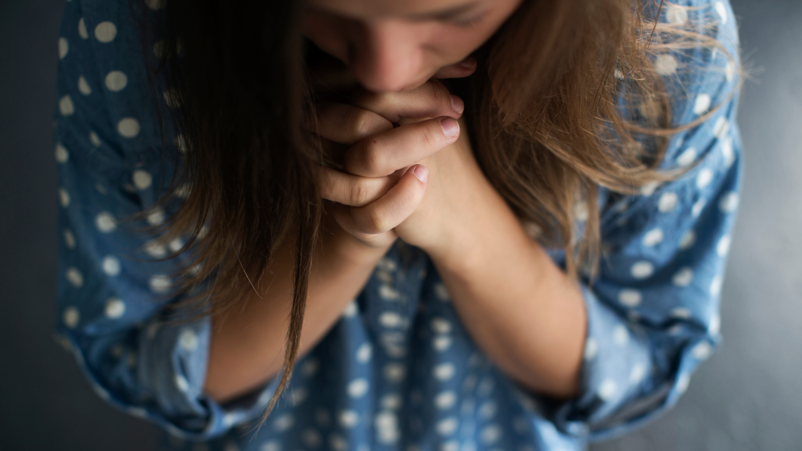 A woman in blue shirt praying.