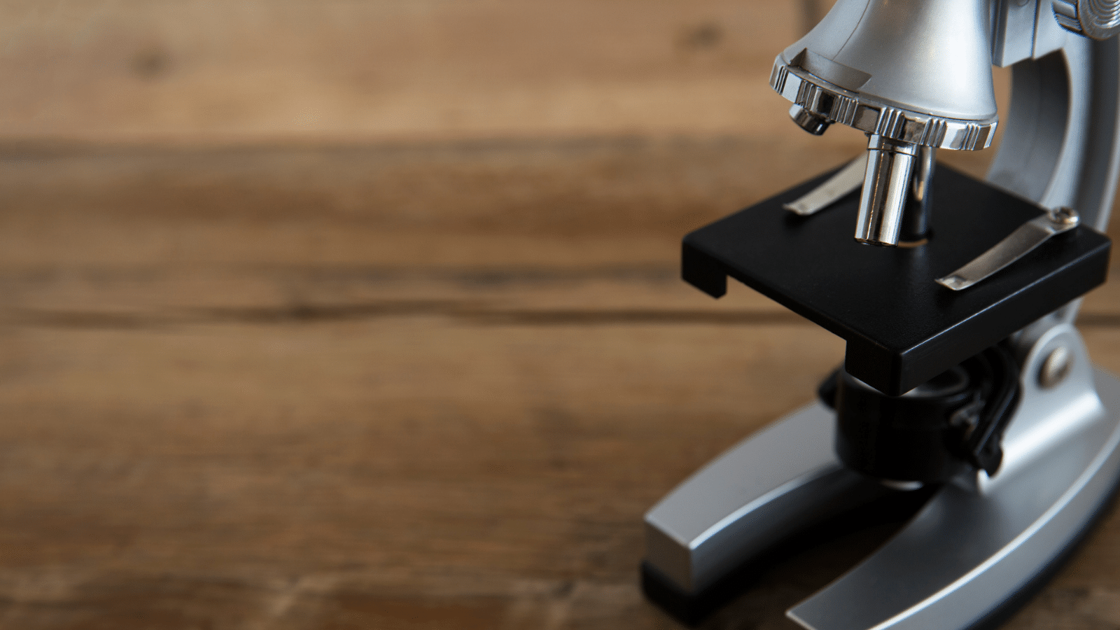 A gray microscope on a wooden table.