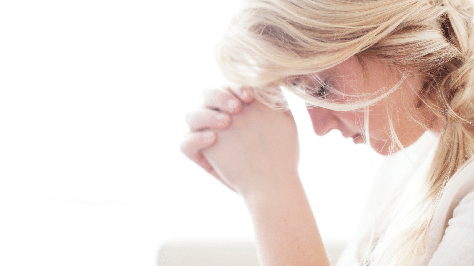 A woman in a white shirt praying.