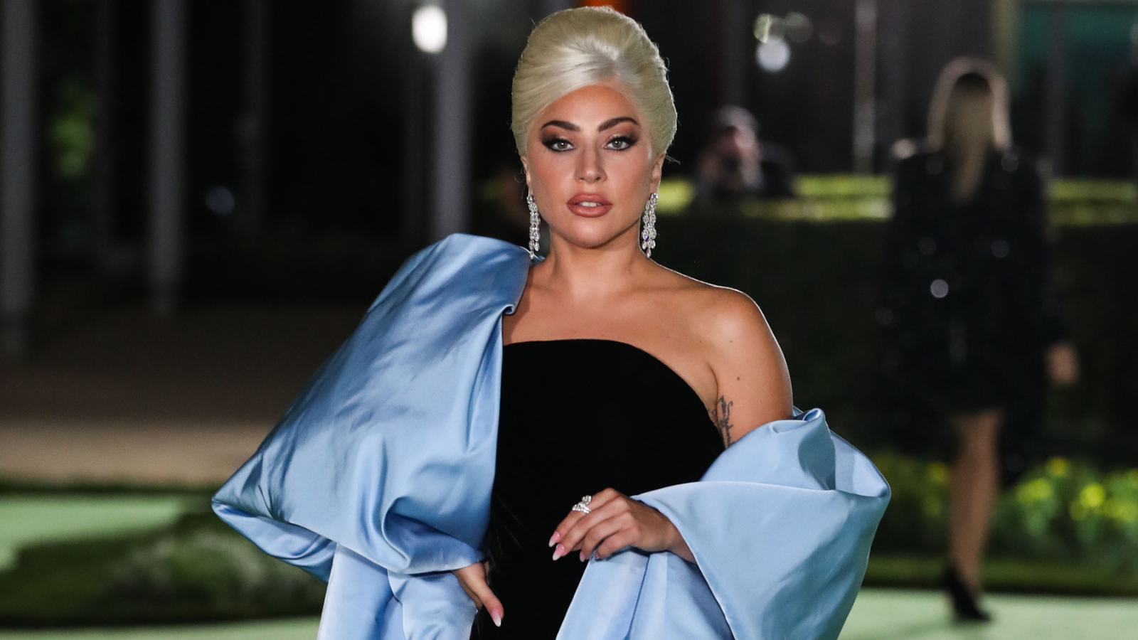 A picture of Lady Gaga in a black dress with a light blue jacket.
