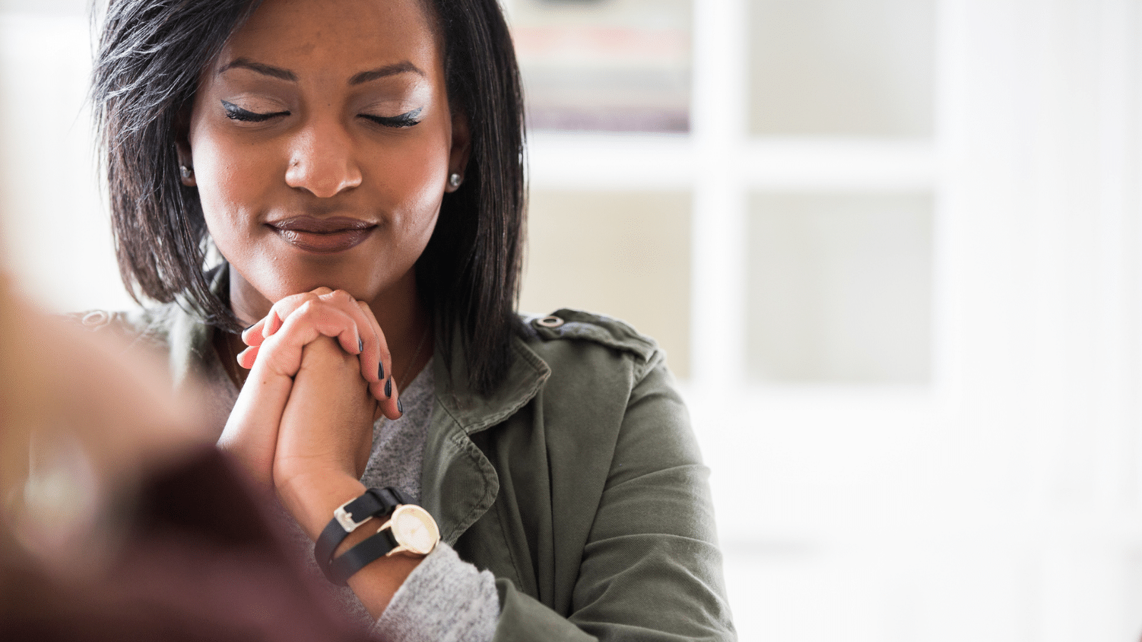 A woman in a gray shirt praying.