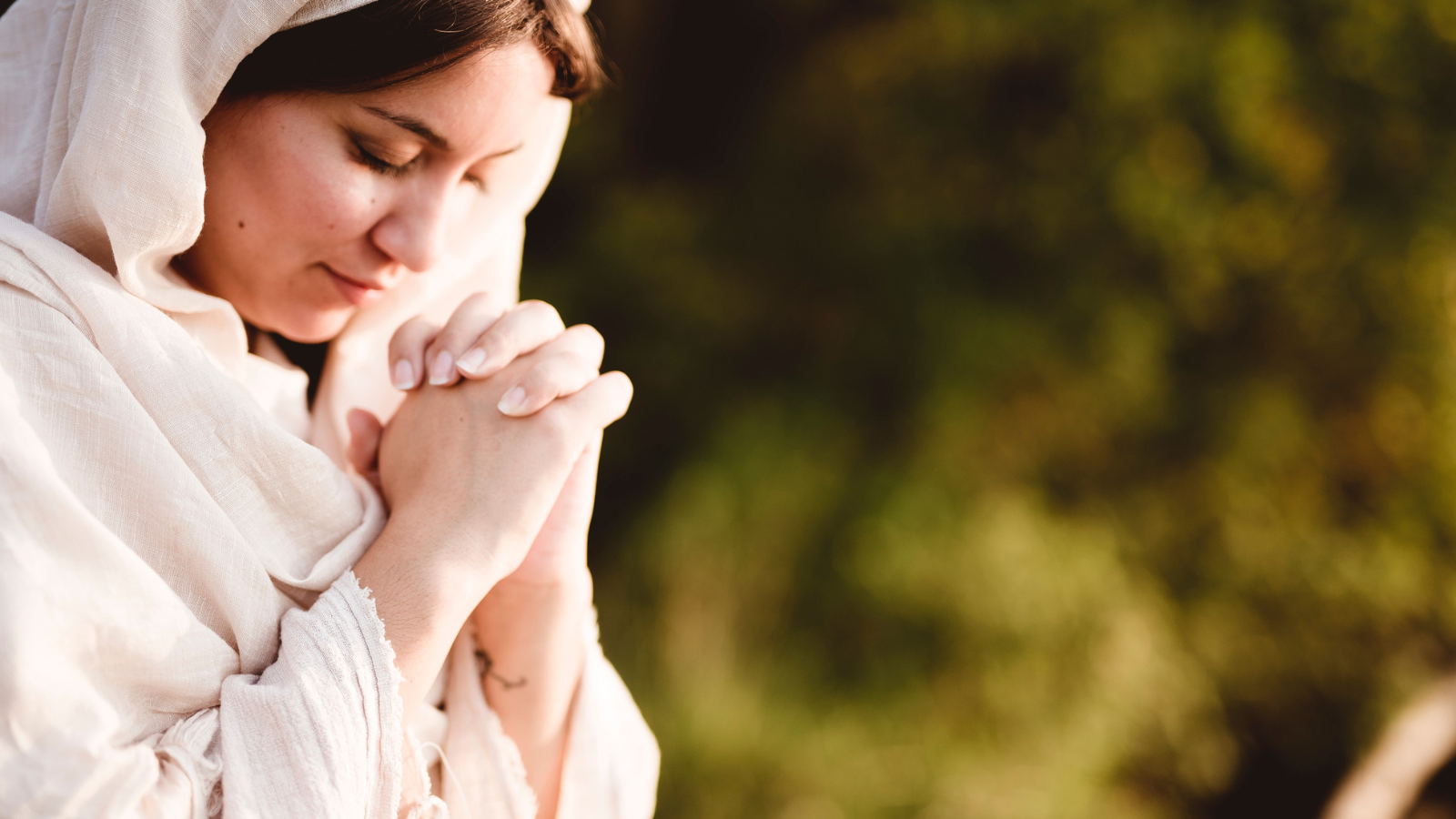 A woman wearing a white cloak and praying.