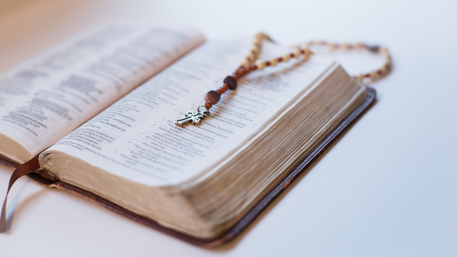 A rosary laying on an open bible.