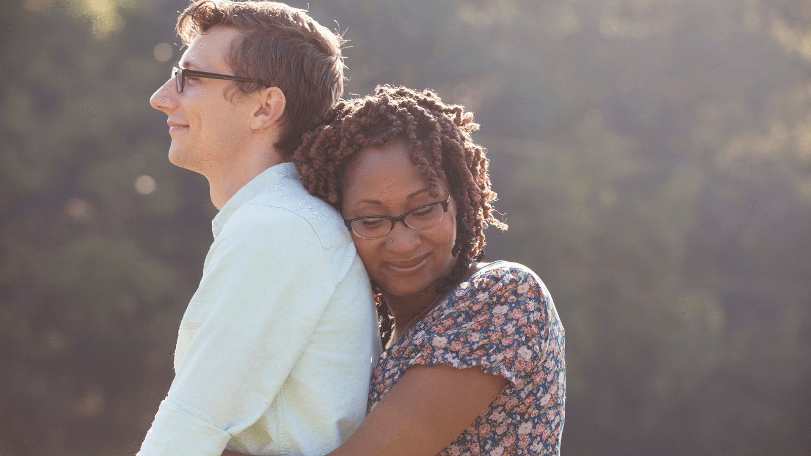 A woman hugging a man from behind.