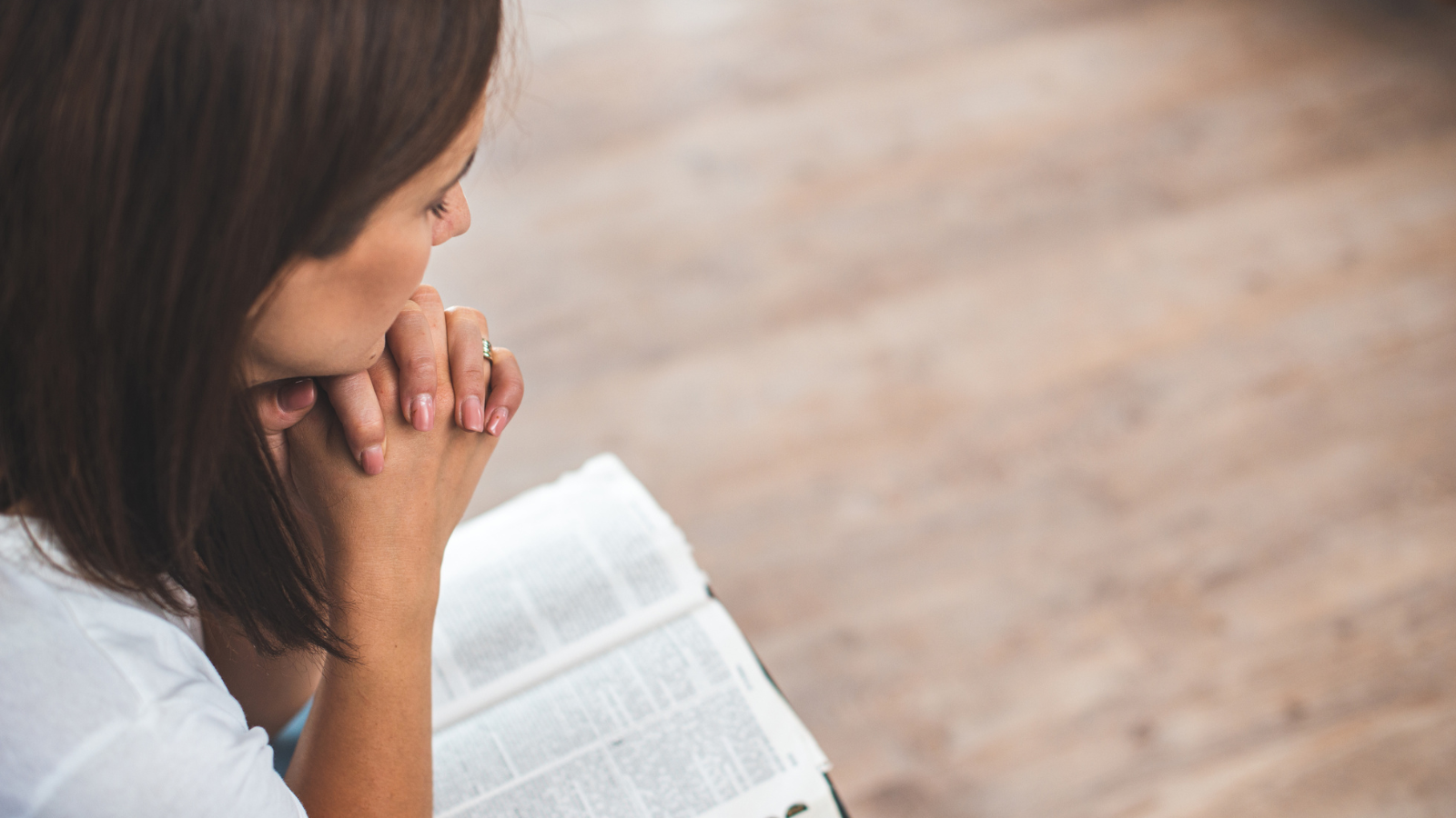 A woman praying over a bible.