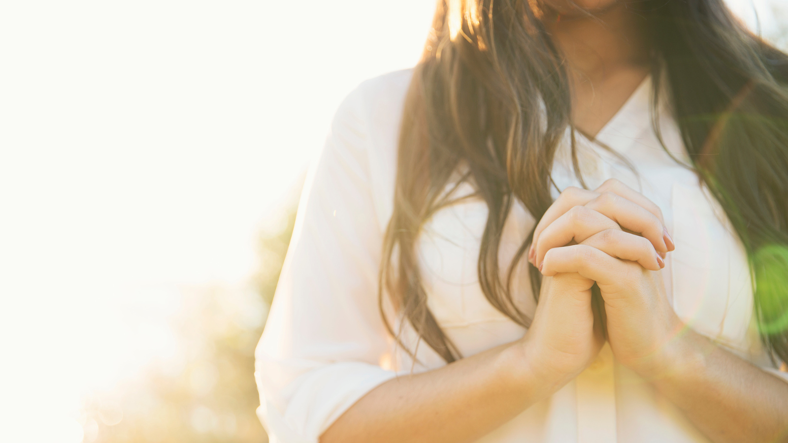 A woman in a white shirt praying.