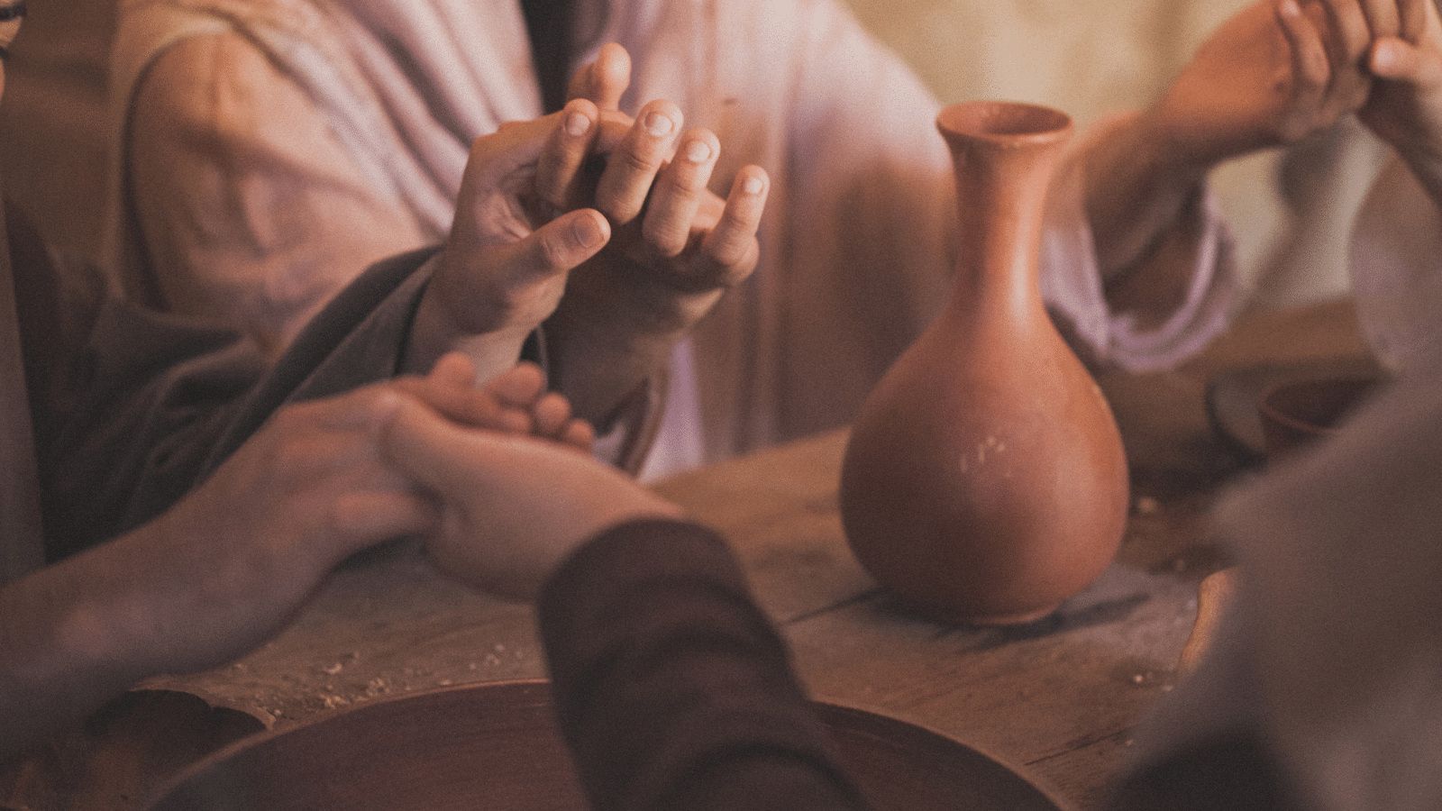 Multiple sets of hands being held around a table.